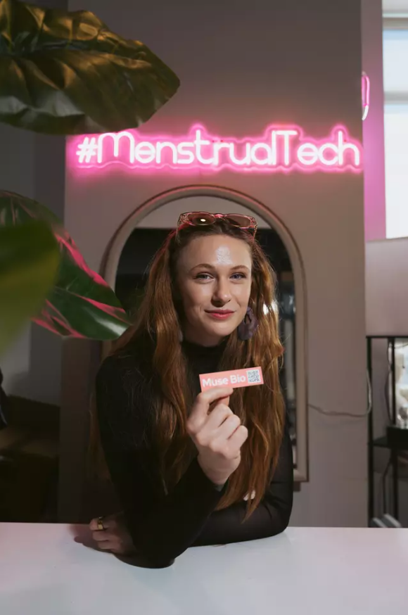 Juliette Humer of Muse Bio beneath a #MenstrualTech neon sign